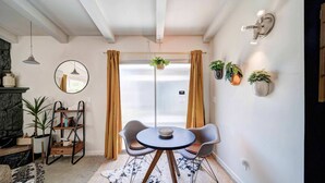 A modern living room with a round table, two chairs, a fireplace, and several potted plants. - Updated Studio near Central Redding w/Hot Tub (Redding)