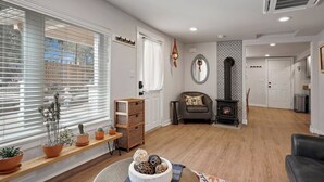 A living room with a fireplace, a sofa, a coffee table with decorative items, and a window with blinds. - Top 5%  - Finnish Sauna - Near Old Mill - No Pets - Fully Remodeled - Quiet (Bend)