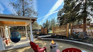 A patio area with two red Adirondack chairs, a fire pit, and a decorative blue hanging ornament. - Top 5%  - Finnish Sauna - Near Old Mill - No Pets - Fully Remodeled - Quiet (Bend)