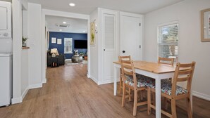 A modern kitchen with white cabinetry, a wooden dining table with four chairs, and a hallway leading to a living area with a blue accent wall. - Top 5%  - Finnish Sauna - Near Old Mill - No Pets - Fully Remodeled - Quiet (Bend)
