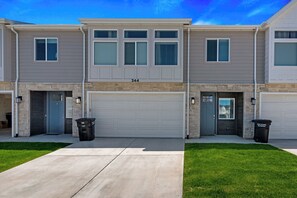 Un immeuble résidentiel à deux étages, doté d’un garage, portant le numéro 344, et comprenant deux poubelles.