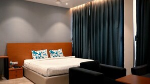 Una camera d'albergo con un letto, un comodino, una scrivania e una sedia.