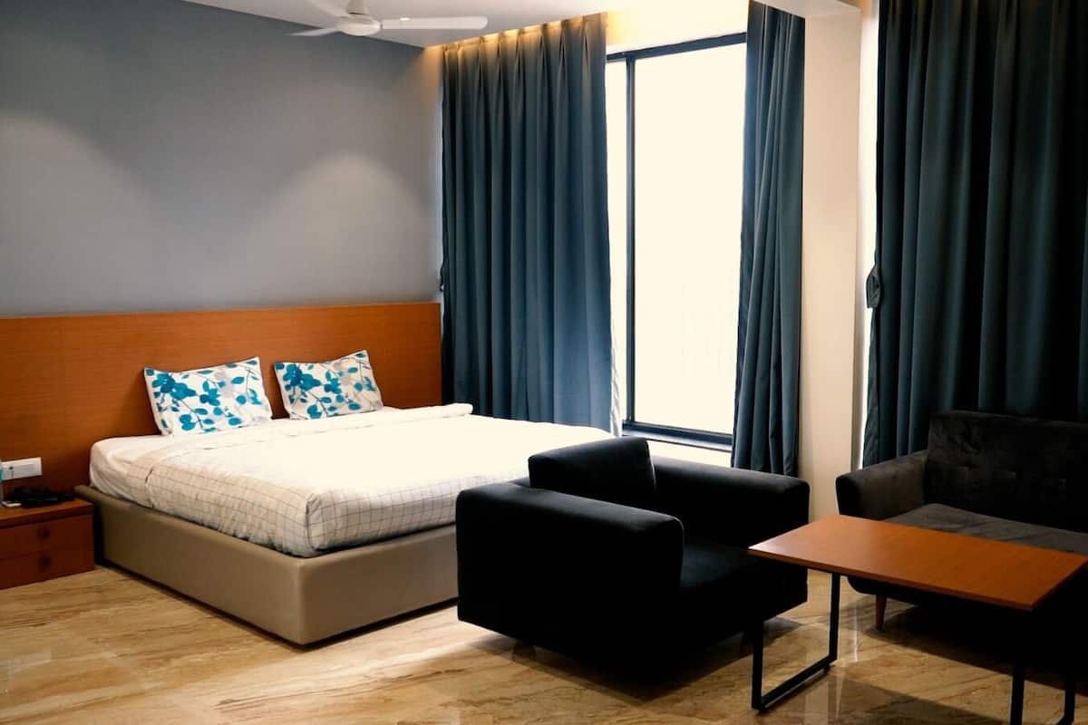 Ein Hotelzimmer mit einem Bett, zwei Sesseln, einem kleinen Tisch und einem Nachttisch.