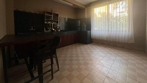 A kitchen with a dining table, chairs, a water dispenser, and a refrigerator. - Gauthali Ghar The Swallow Home (Kathmandu)