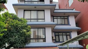 A multi-story building with a flat roof, satellite dish, and a balcony with hanging plants. - Gauthali Ghar The Swallow Home (Kathmandu)