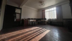 A spacious living room with a large sofa, a coffee table, and a fireplace. - Gauthali Ghar The Swallow Home (Kathmandu)
