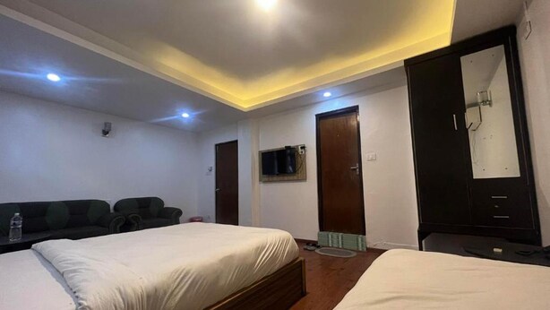 A hotel room with two beds, a television mounted on the wall, and a wardrobe. - Gauthali Ghar The Swallow Home (Kathmandu)