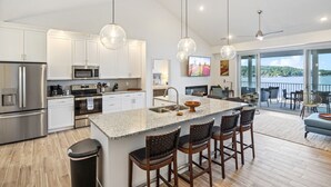 A modern kitchen with a large island, stainless steel appliances, and a view to the outside.
