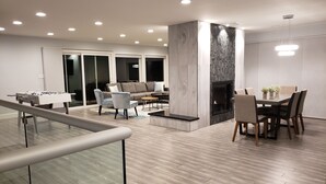 Uma sala de estar moderna com lareira, uma área de jantar com mesa e cadeiras, e uma mesa de futebol.