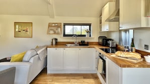 Een moderne keuken met een centraal eiland, geïntegreerde apparatuur en een raam boven de spoelbak.