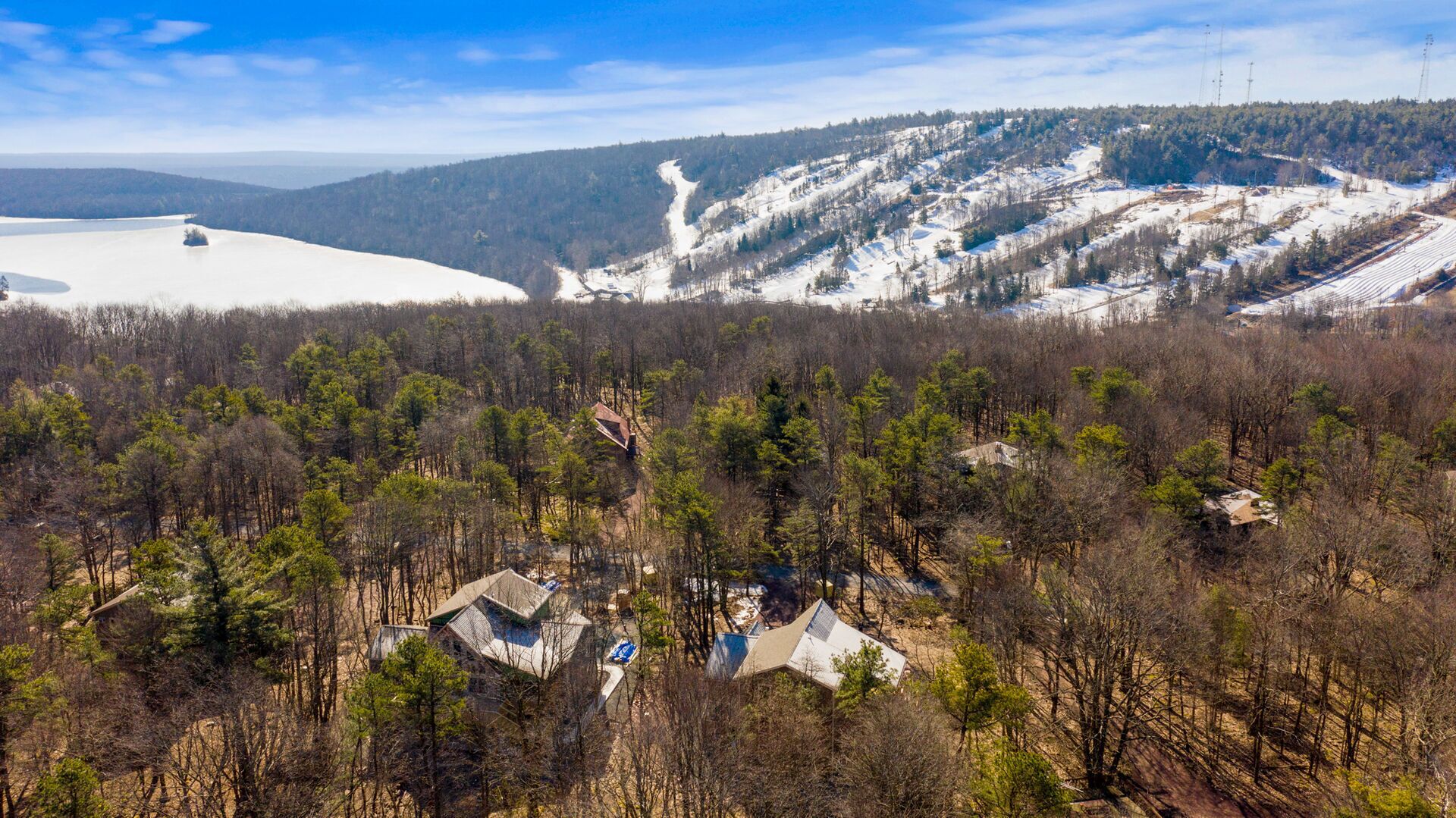 A mountainous landscape with a ski resort, forested areas, and a few buildings.