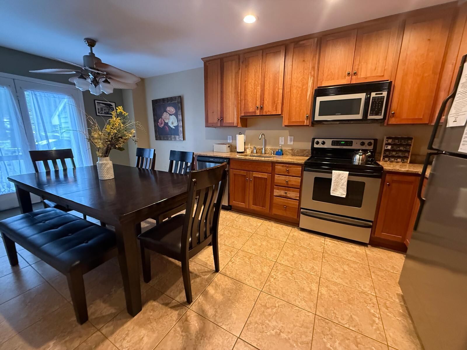 A kitchen with wooden cabinets, a stove, a microwave, and a dining area with a table and chairs.