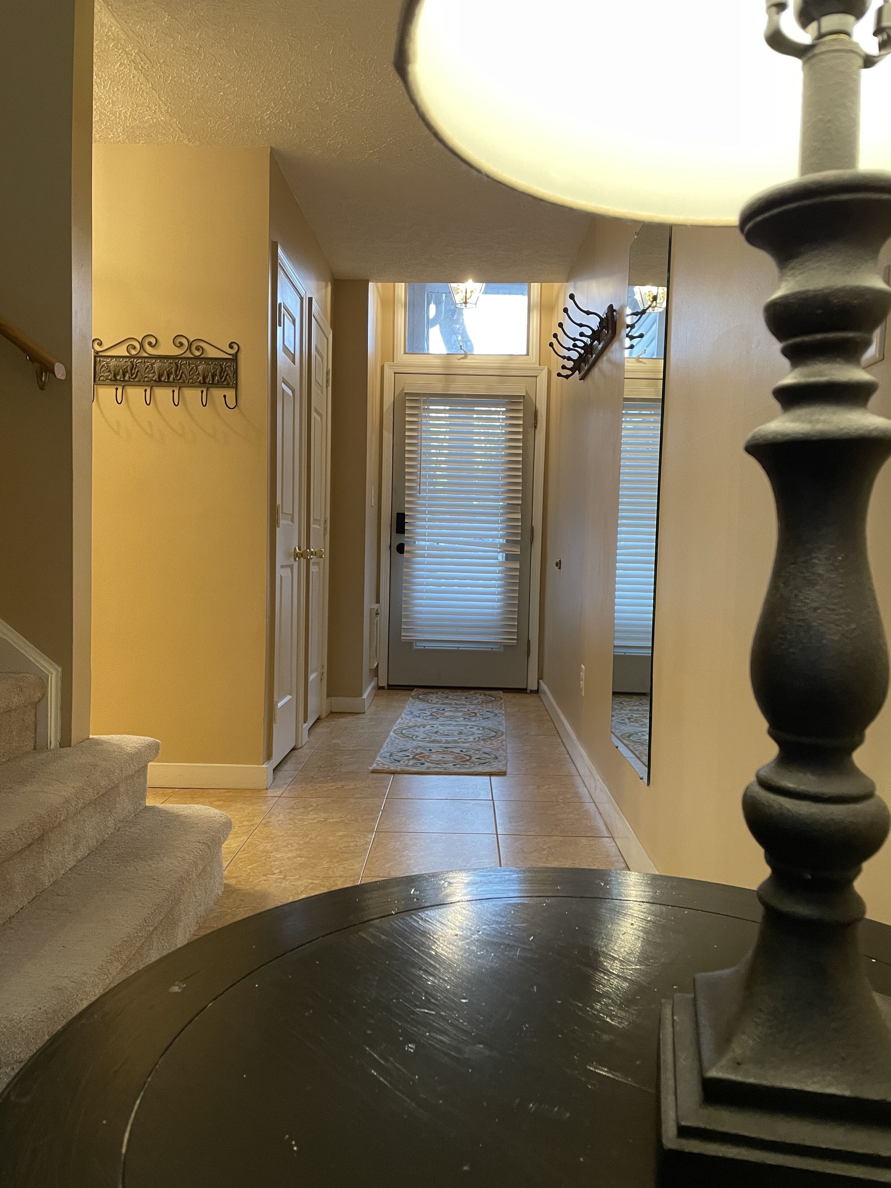 A hallway with a door, a rug, and a wall-mounted light fixture.