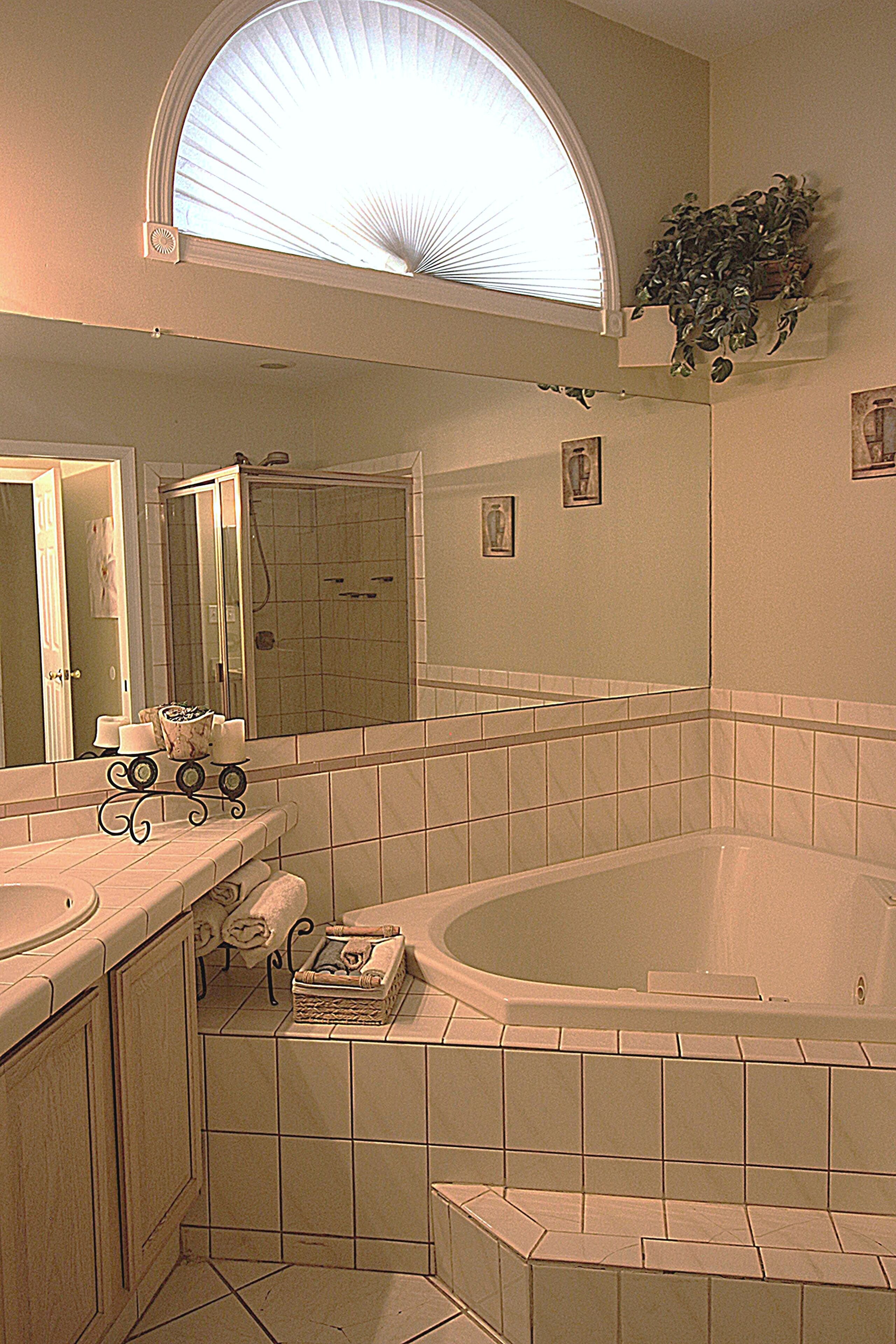A bathroom with a large bathtub, a shower, and a vanity with a mirror.