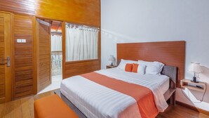 A bedroom with a wooden headboard, a bed with white and orange bedding, a nightstand with a lamp, and a wooden wardrobe. - Villa Padma Nusa Dua (Nusa Dua)