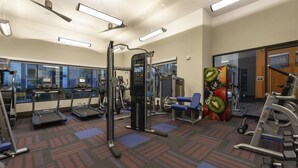 Ein Fitnessstudio mit Laufbändern, Kraftgeräten und einem blauen Stuhl.