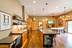 A spacious kitchen with wooden cabinets, a central island, and pendant lighting. - Crosslake Barndominium (Crosslake)