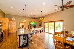 A spacious kitchen with wooden cabinets, a central island, and a dining area with a large table and chairs. - Crosslake Barndominium (Crosslake)