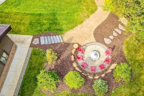 An aerial view of a landscaped outdoor area with a circular seating arrangement, surrounded by various shrubs and a pathway leading to a building. - Crosslake Barndominium (Crosslake)