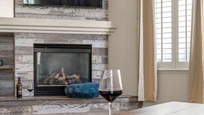 A living room with a fireplace, a glass of red wine, and a blue ottoman. - Family Friendly Game House BBQ Pool Table Tahoe (Reno)