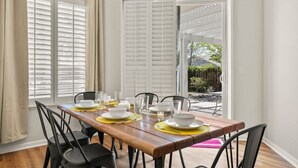 A dining area with a wooden table set for four, white chairs, and a view of a garden through a door. - Family Friendly Game House BBQ Pool Table Tahoe (Reno)