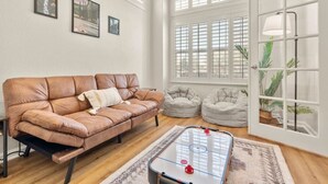 A living room with a brown leather sofa, two bean bags, a foosball table, and a large window with blinds. - Family Friendly Game House BBQ Pool Table Tahoe (Reno)
