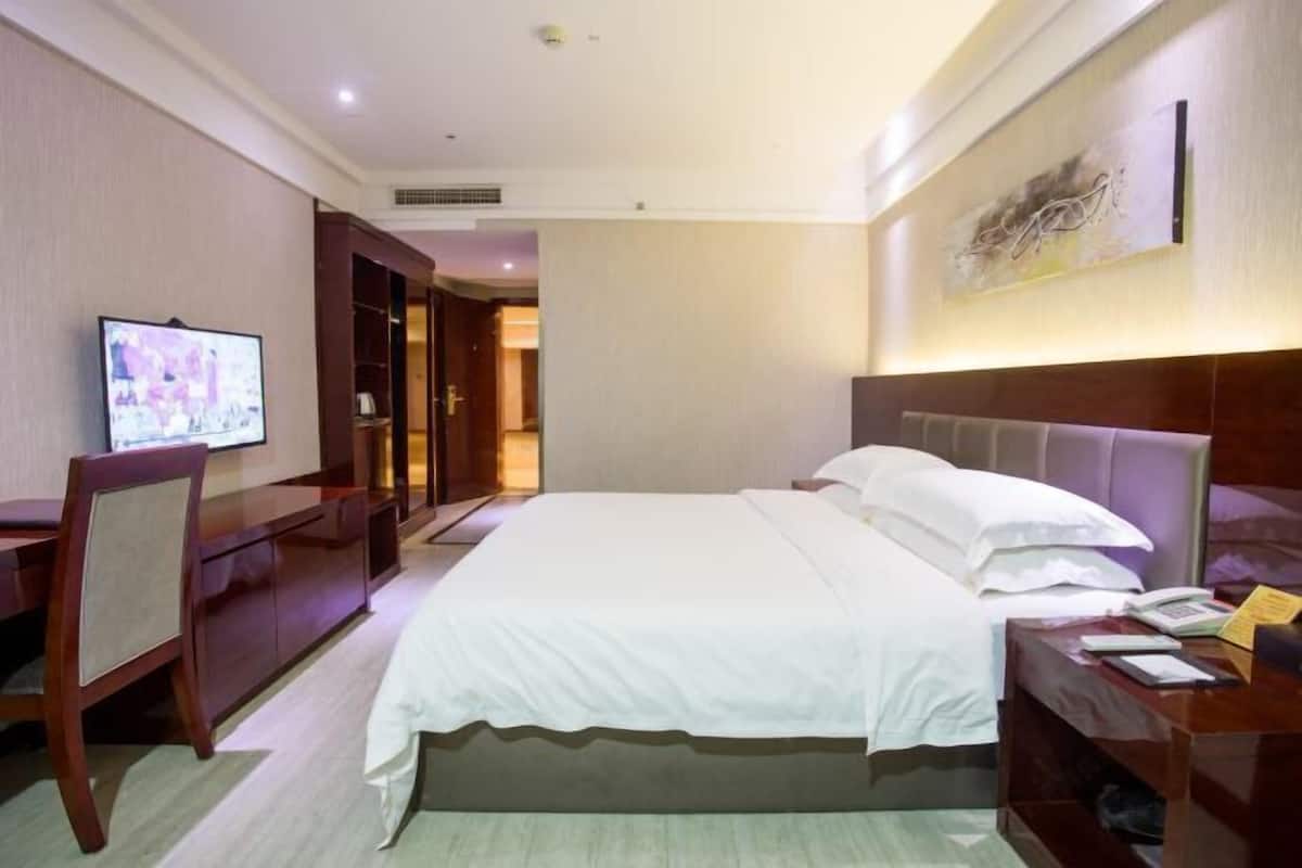 Une chambre d’hôtel équipée d’un lit, d’un bureau, d’une télévision et d’une armoire.