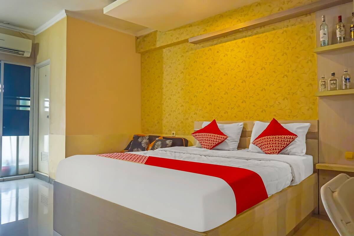 A hotel room with a large bed, a bedside table, a chair, and a window with a view.