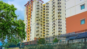 A multi-story residential building with balconies, a paved road, and a fence. - OYO 92292 Nadjla Property Cibubur Village (Depok)
