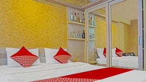 A hotel room with a bed, red and white patterned bedspread, and a wardrobe with shelves of toiletries. - OYO 92292 Nadjla Property Cibubur Village (Depok)