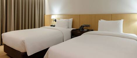 Une chambre d’hôtel avec deux lits, une table de chevet, une lampe et un téléphone.