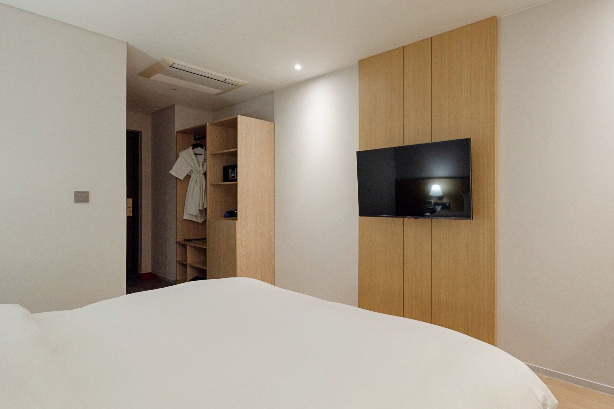 A bedroom with a bed, a TV mounted on a wooden wall, and a walk-in closet.