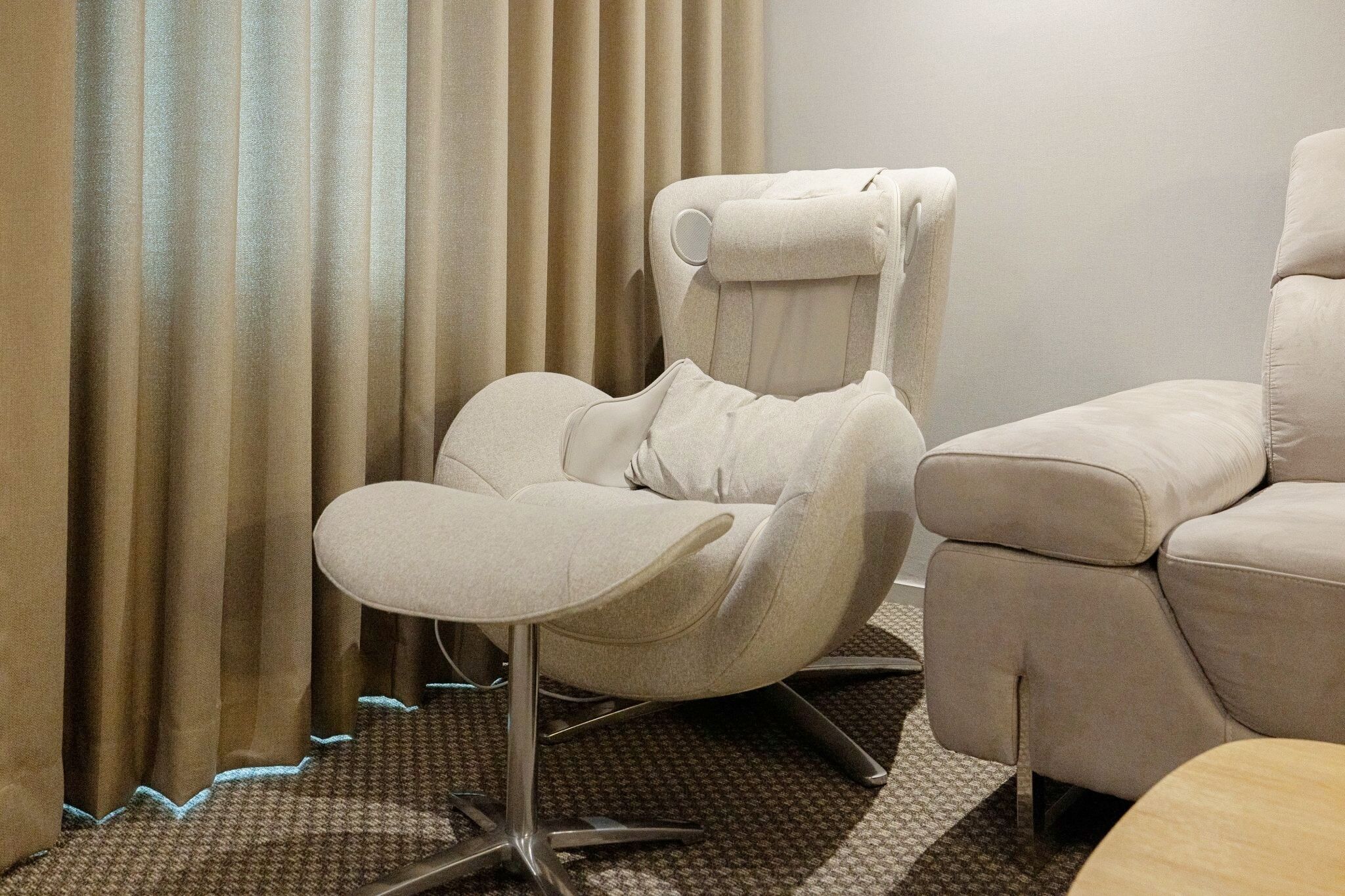 A room with a massage chair, a sofa, and a patterned carpet.