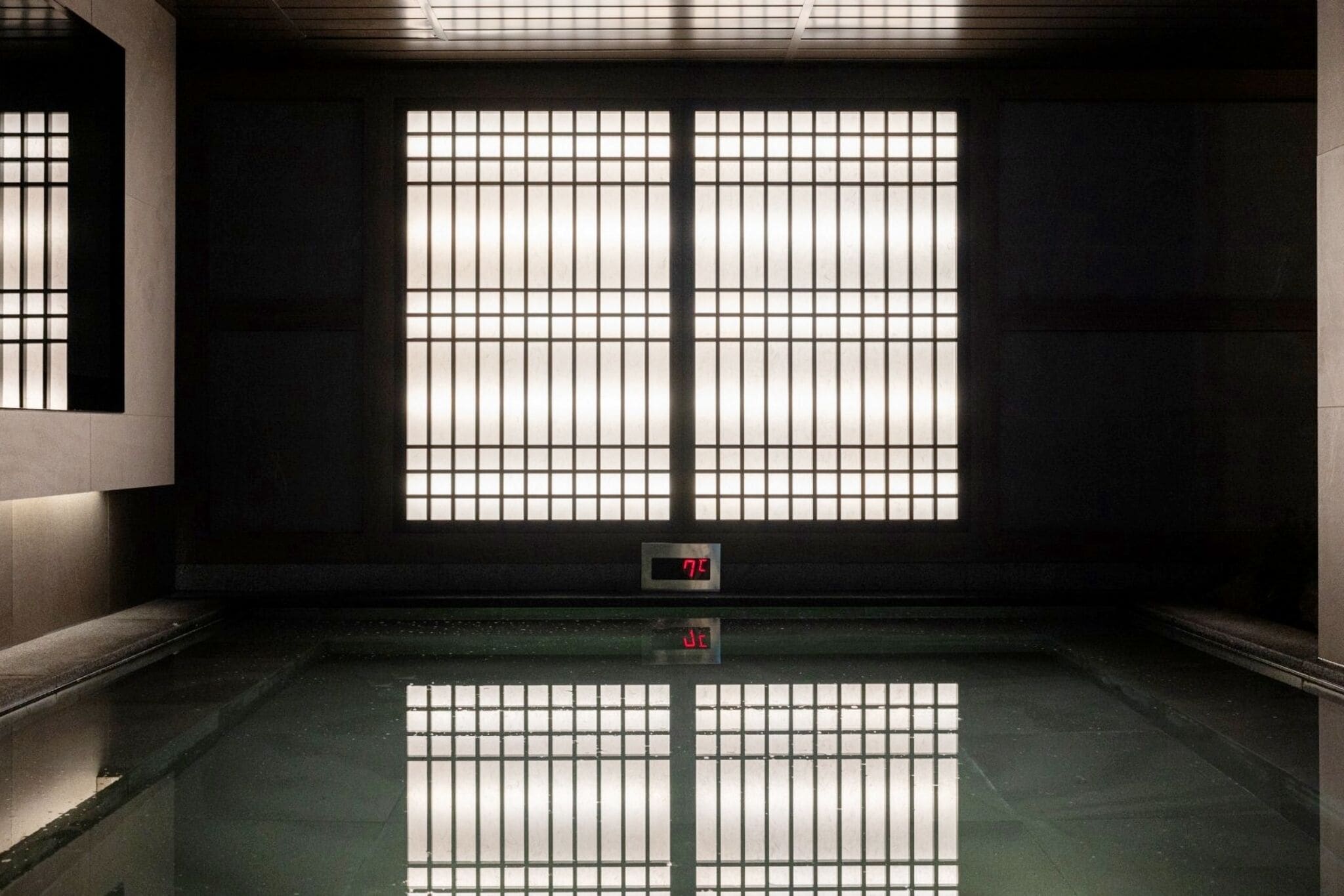 A room with a large window, a digital clock, and a reflective floor.