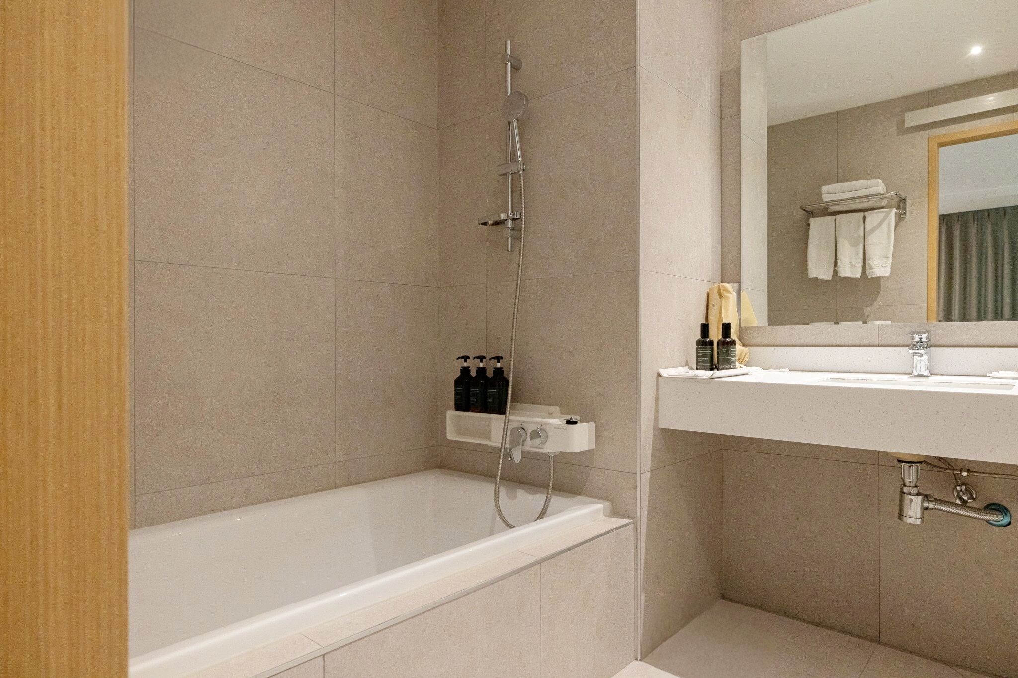 Un baño moderno con bañera, ducha, tocador con espejo y perchero.