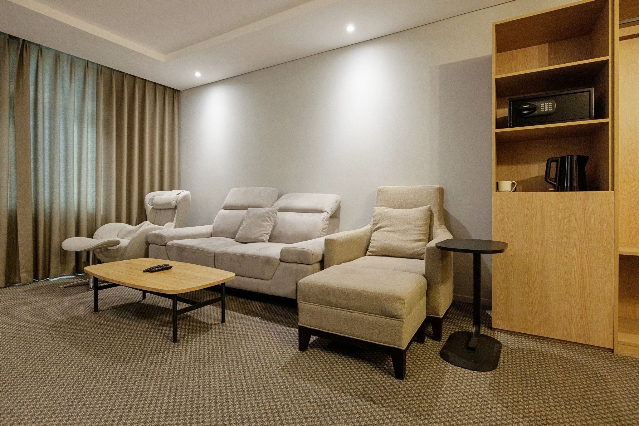A hotel room with a sofa, armchair, coffee table, and a small side table.