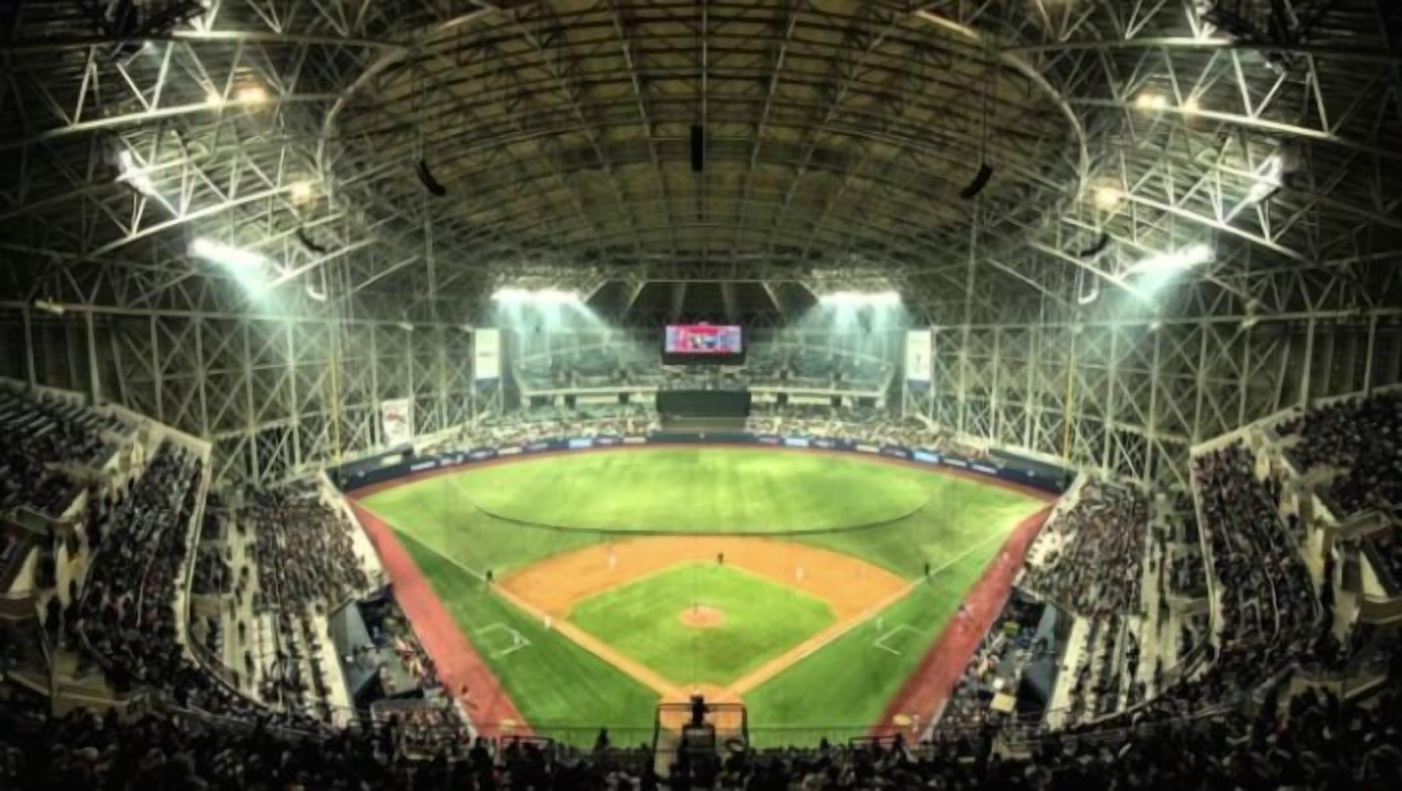 A large stadium with a baseball field, multiple tiers of seating, and a large scoreboard.
