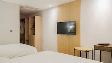 A modern hotel room with a bed, a TV, a small table, and a wardrobe.