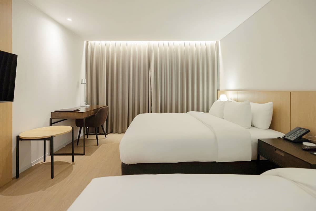 Una habitación de hotel con cama, escritorio, silla, lámpara y teléfono.