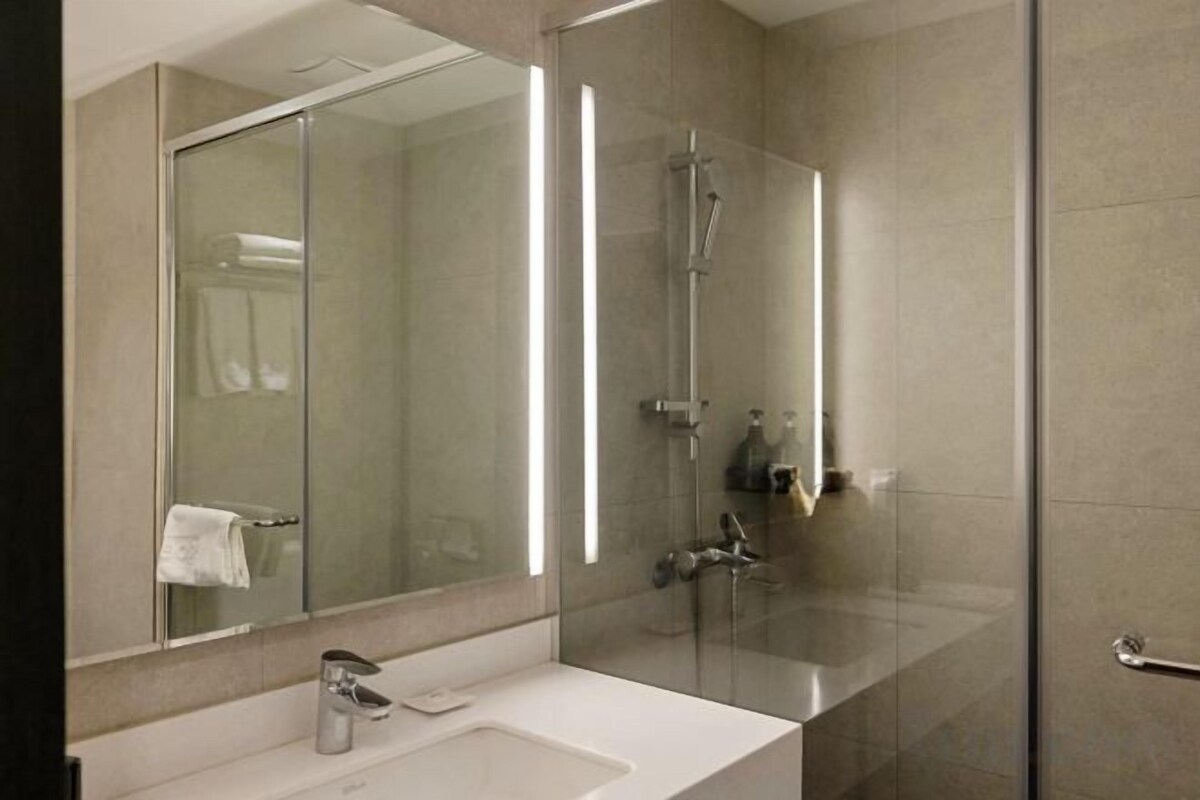 A modern bathroom with a glass shower enclosure, a sink, and a mirror.