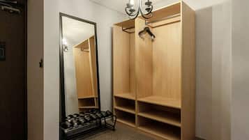 Een hotelkamer met een grote spiegel, een houten garderobe en een schoenenrek.