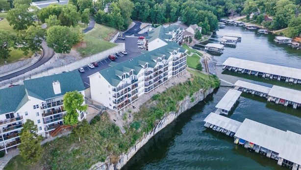 A waterfront hotel with multiple balconies, a parking area, and boats docked along the shore.