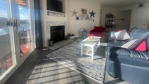 A living room with a fireplace, a ceiling fan, and a red armchair.