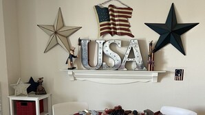A dining area with a round table, white chairs, and a USA-themed decoration above the table.