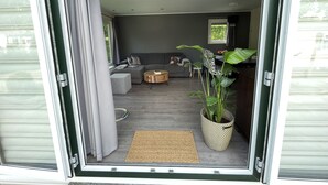 A modern living room with a grey sofa, a round coffee table, and a large potted plant. - Forest Family Home - 6 Persoons op 5 Sterren Park (Beekbergen)