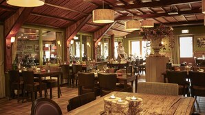 A restaurant with wooden beams, hanging lamps, and a bar area with bottles and glasses. - Forest Family Home - 6 Persoons op 5 Sterren Park (Beekbergen)