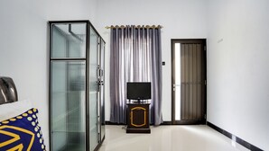 Habitación de hotel con una cama, un televisor sobre un mueble de madera, un armario y una puerta.