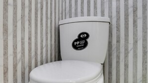 Un inodoro con una etiqueta de PP, papel tapiz a rayas y baldosas de suelo estampadas.