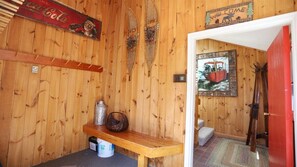 A wooden interior with a bench, a Coca-Cola sign, a welcome sign, and a framed picture of a vehicle.