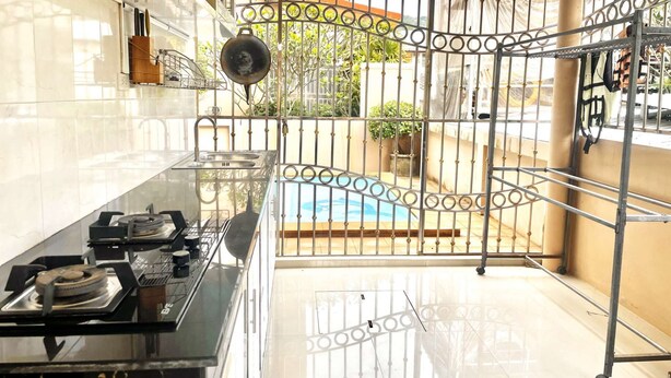 A kitchen with a gas stove, a sink, and a metal gate leading to a pool area.